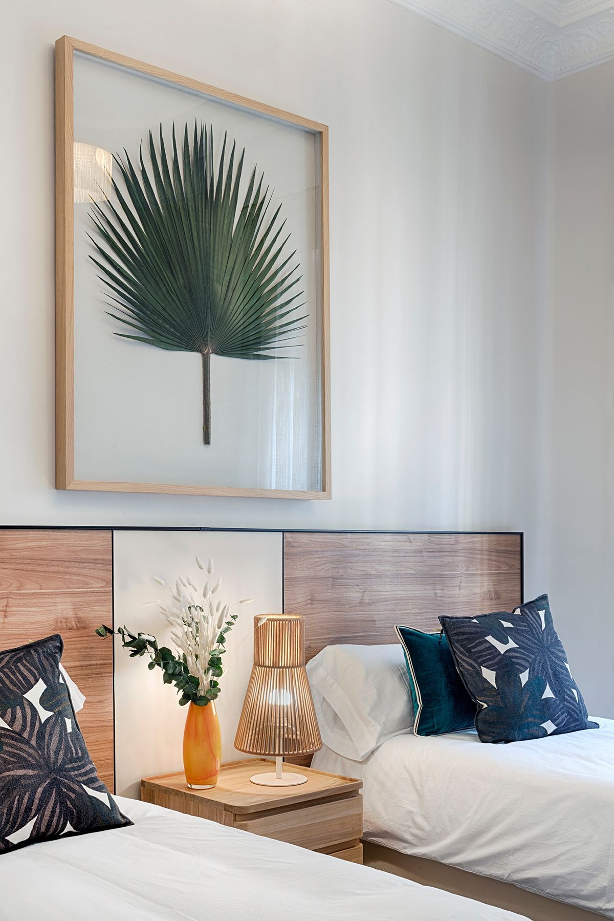 Hay una imagen de una palmera en la pared encima de la cama.