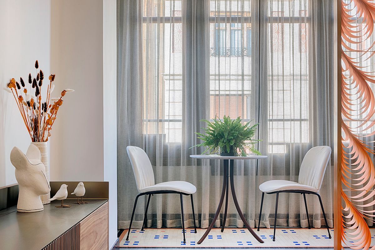 Una sala de estar con una mesa y sillas frente a una ventana.