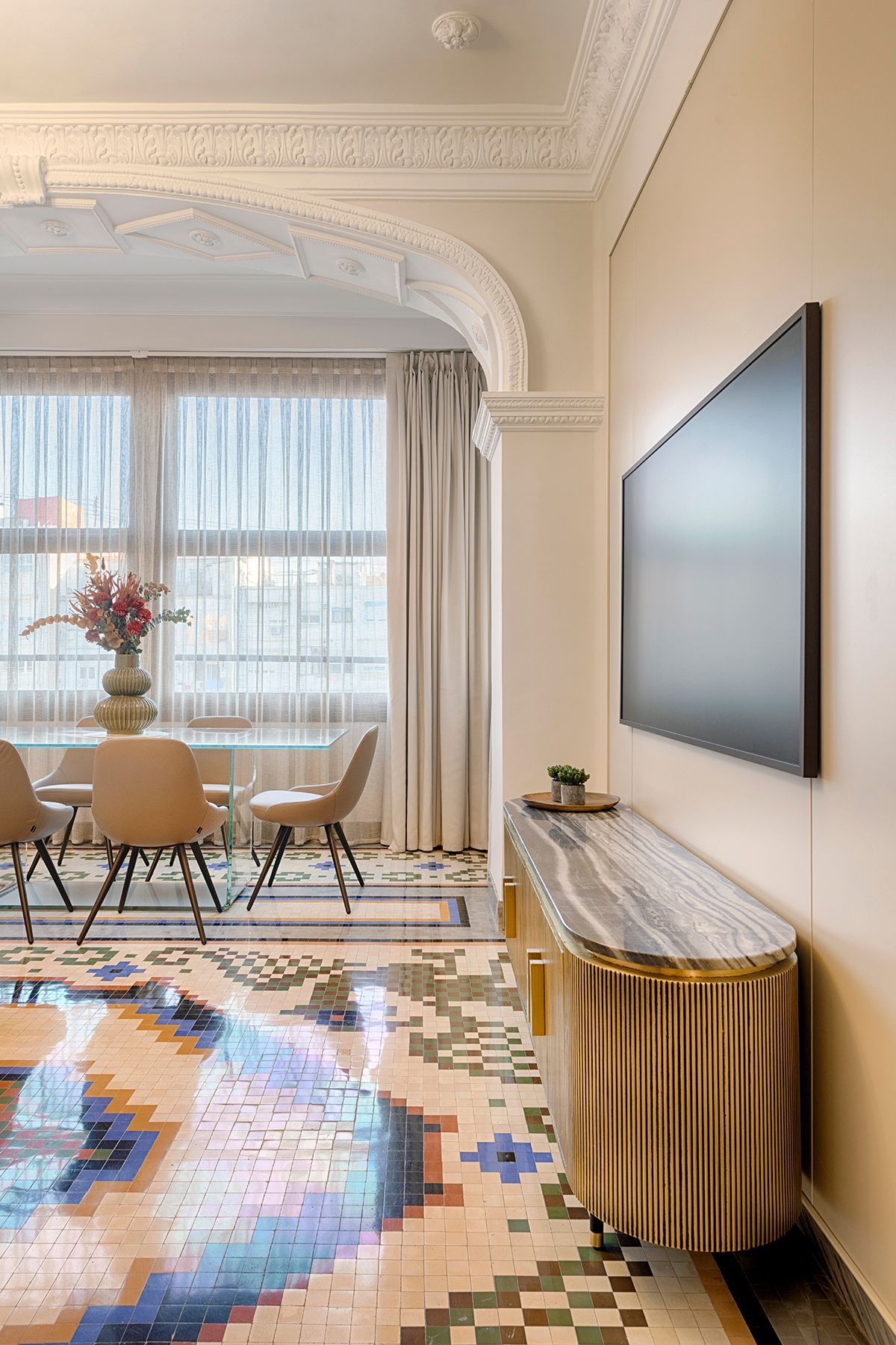 Una sala de estar con una mesa de comedor y sillas y un televisor de pantalla plana en la pared.