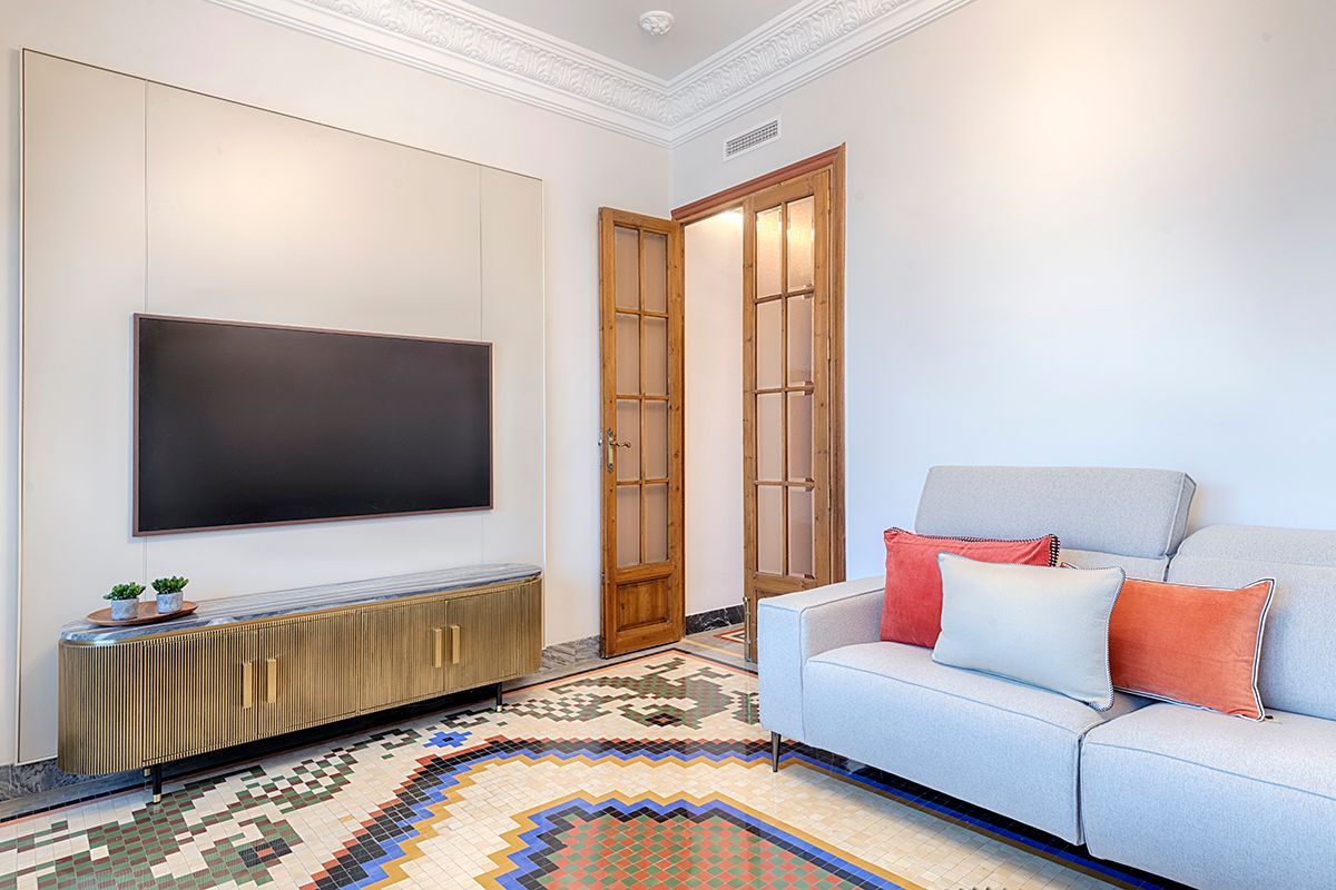 Una sala de estar con sofá, televisión y alfombra.