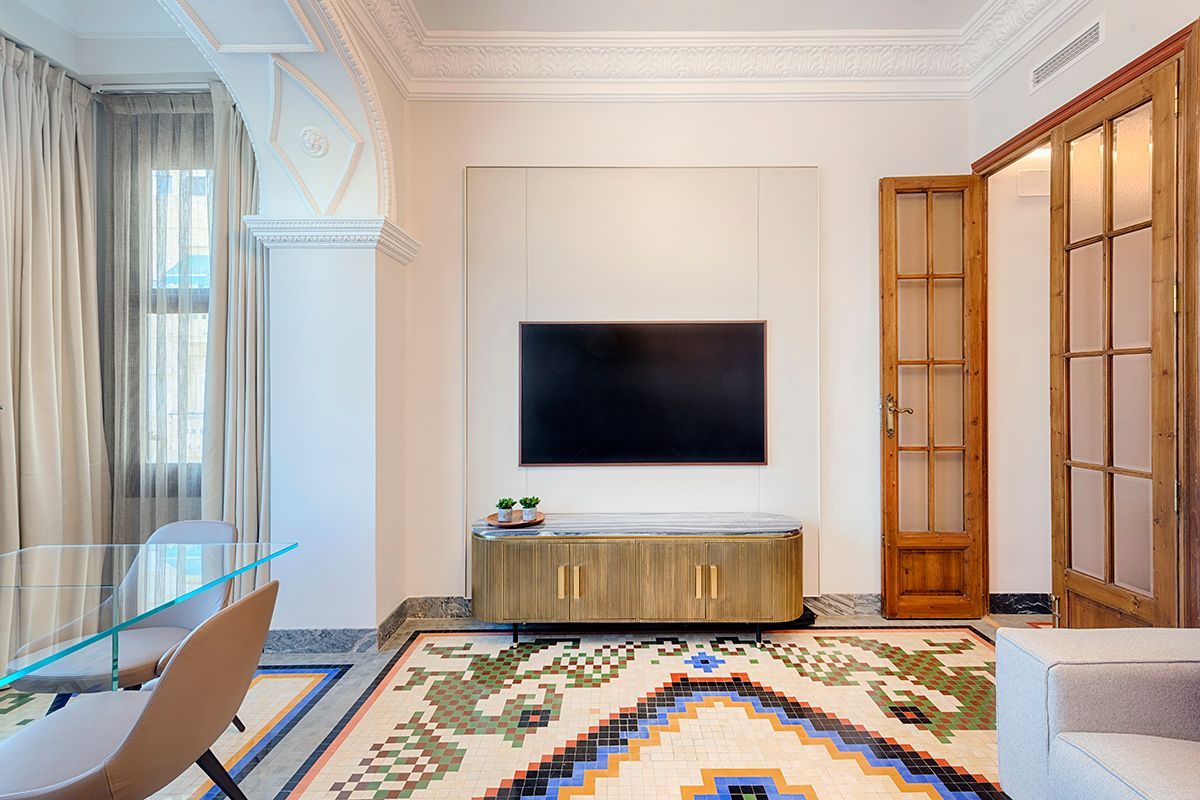 Una sala de estar con una alfombra y un televisor de pantalla plana en la pared.