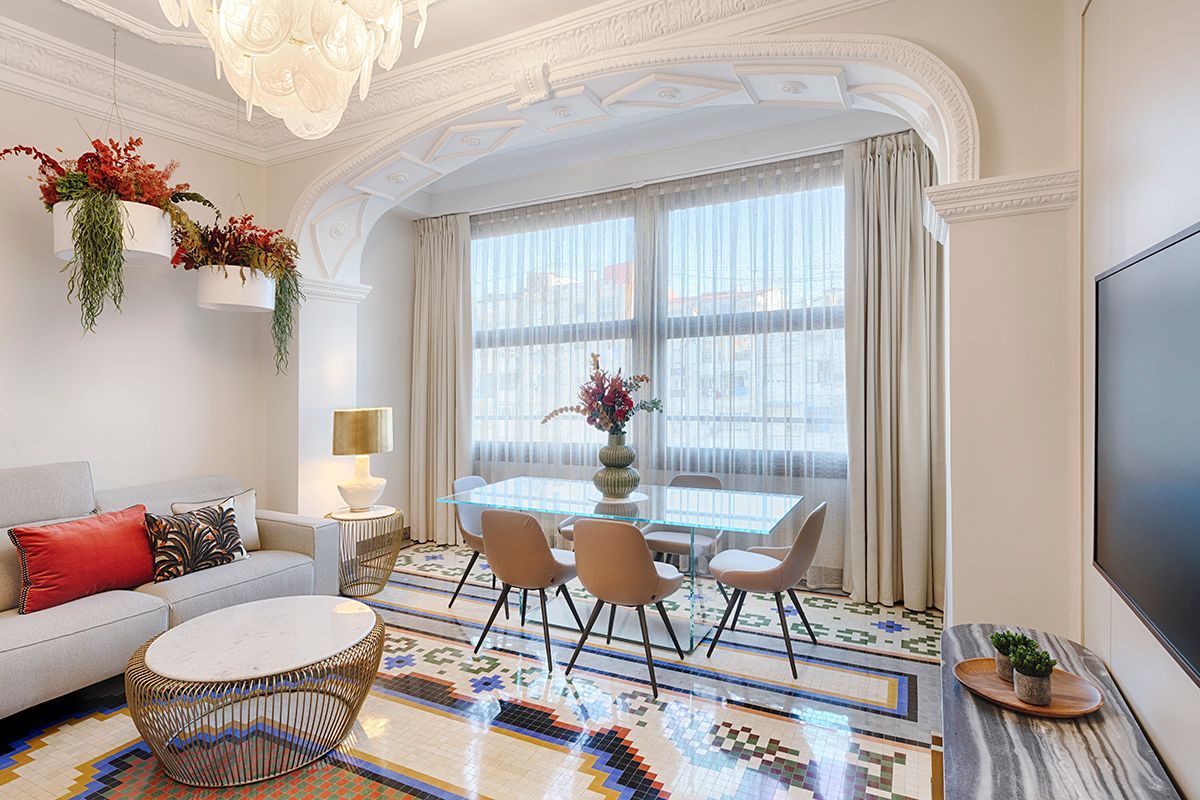 Una sala de estar con un sofá, una mesa, sillas y una lámpara de araña.