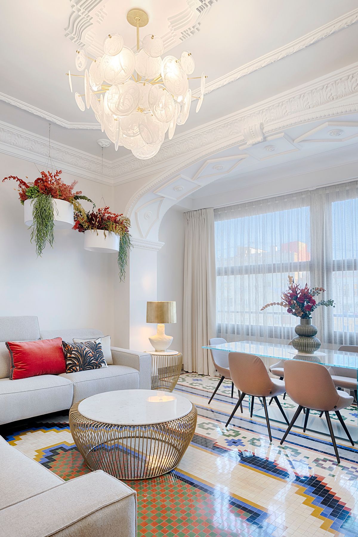 Una sala de estar con un sofá, una mesa, sillas y una lámpara de araña.