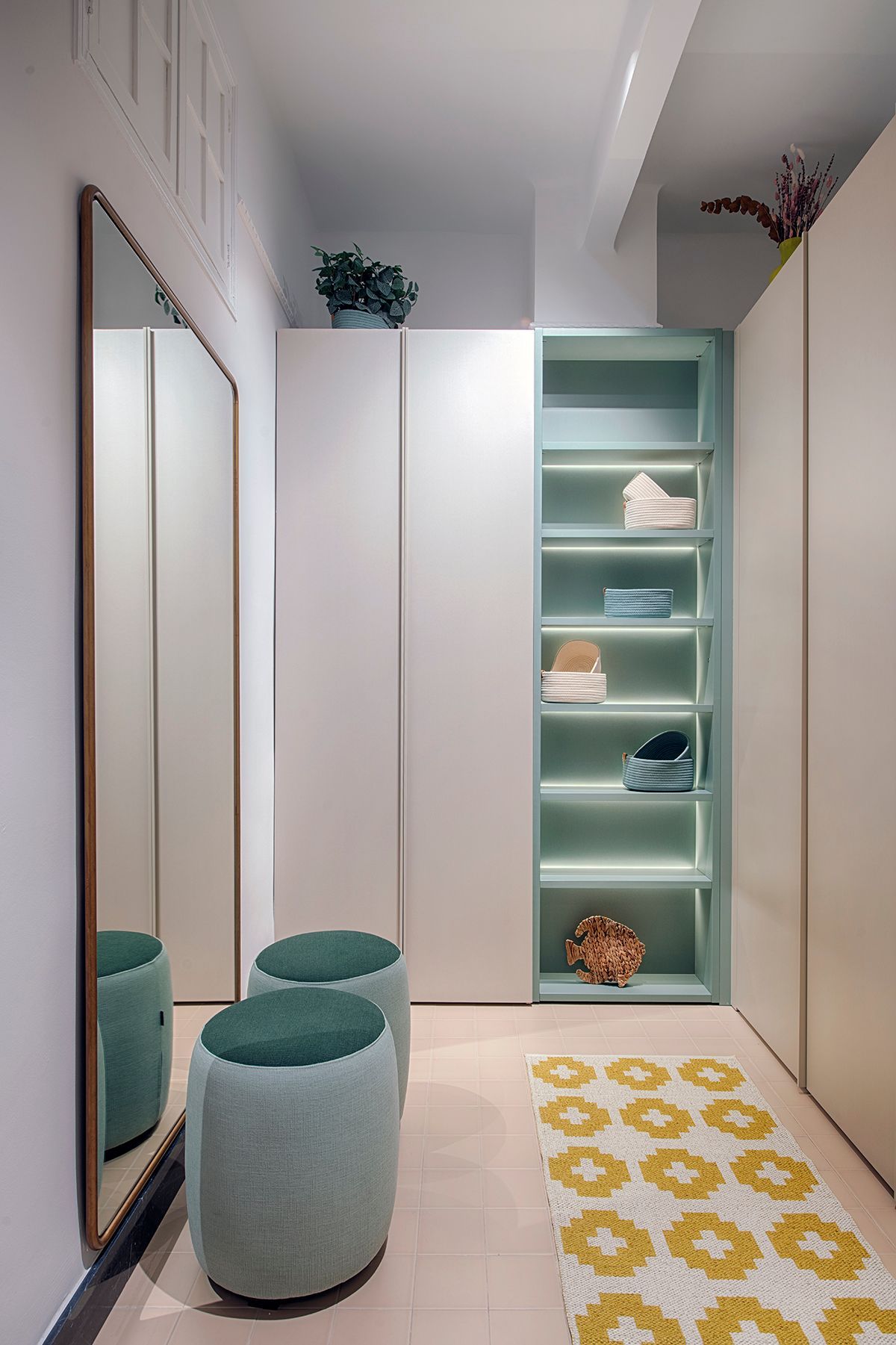 Un vestidor con un gran espejo, otomanas, estantes y una alfombra.