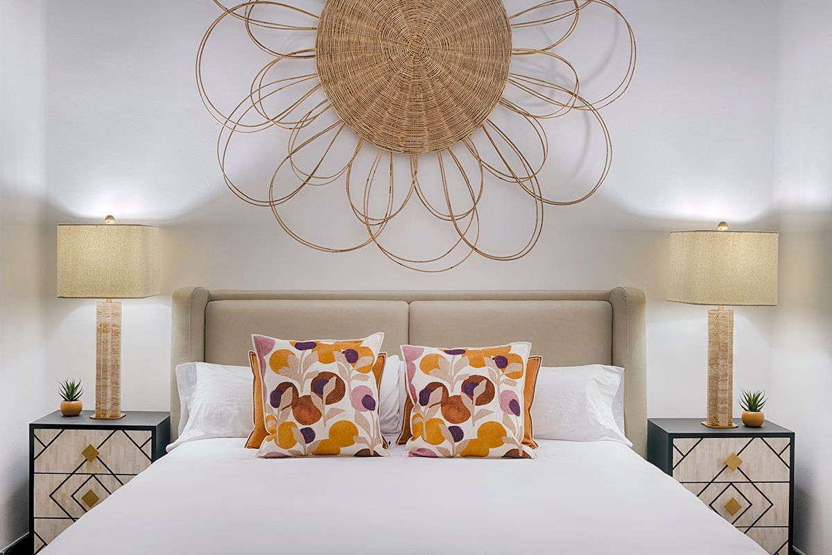 Un dormitorio con una cama, mesitas de noche, lámparas y una decoración de pared.