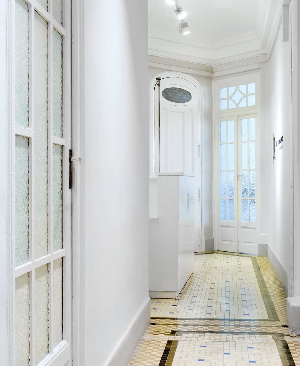 Un pasillo con paredes blancas y suelo de baldosas.