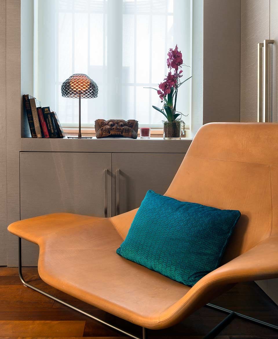 Una silla con una almohada azul delante de una ventana.