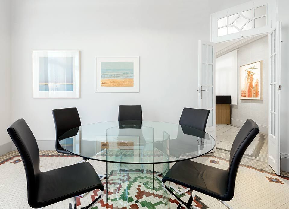 Un comedor con una mesa redonda de cristal y sillas negras.