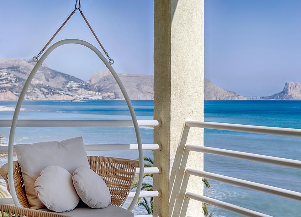 Una silla colgante en un balcón con vista al mar.