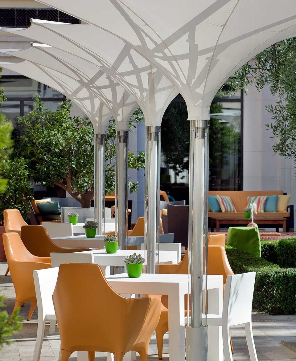 Una fila de mesas y sillas bajo sombrillas blancas