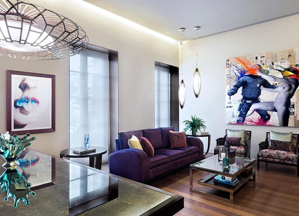 Una sala de estar con un sofá morado y un cuadro en la pared.