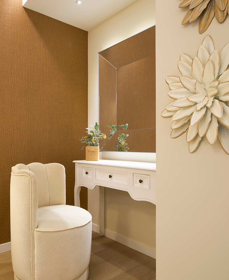 Una habitación con una silla y un tocador con flores en la pared.