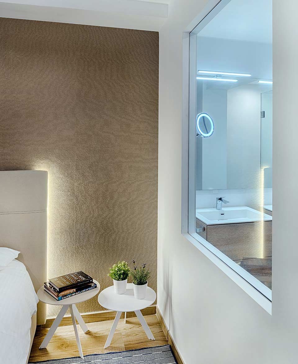 Un dormitorio con vista a un baño a través de una ventana.