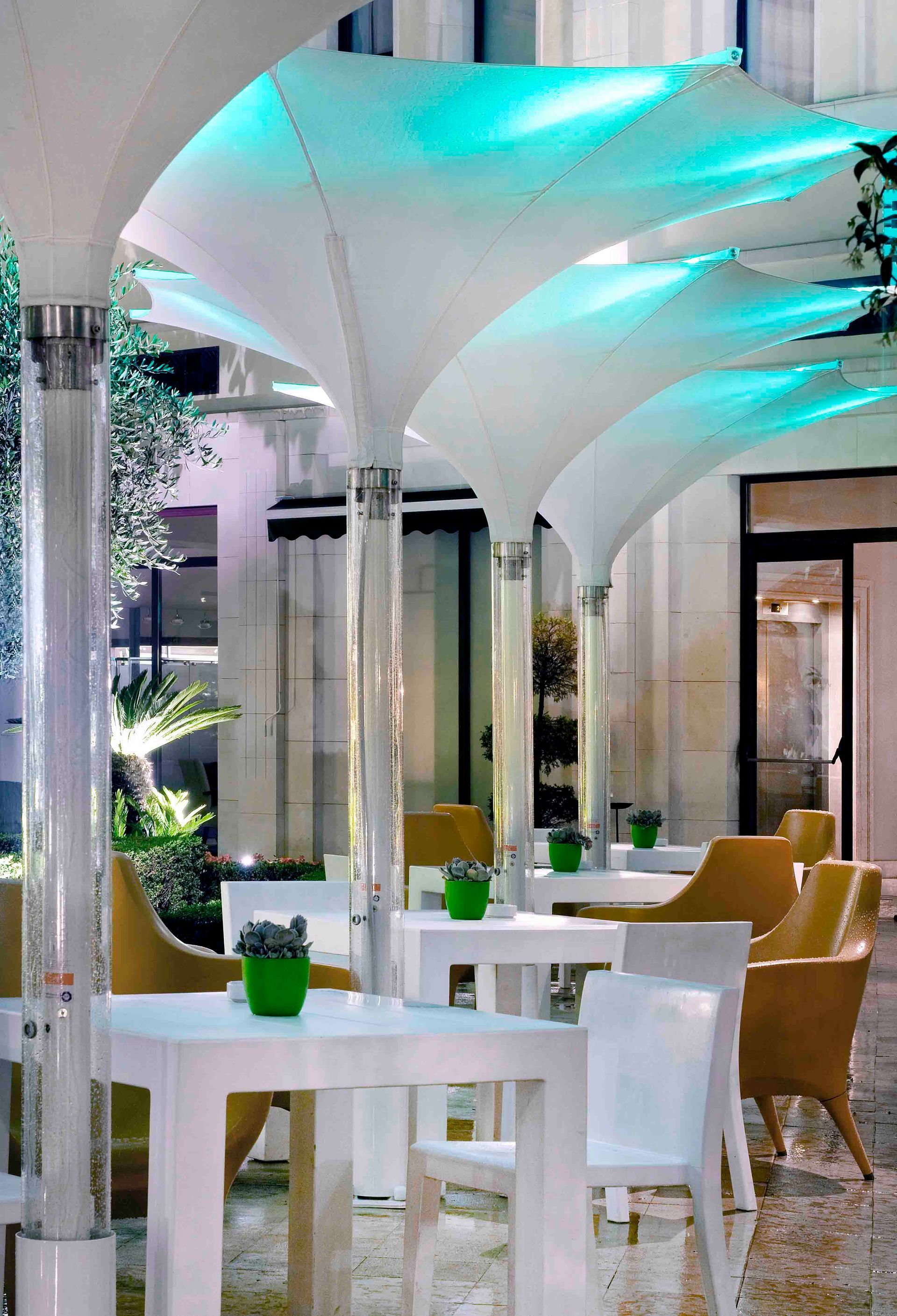 Un restaurante con mesas y sillas bajo una sombrilla azul.
