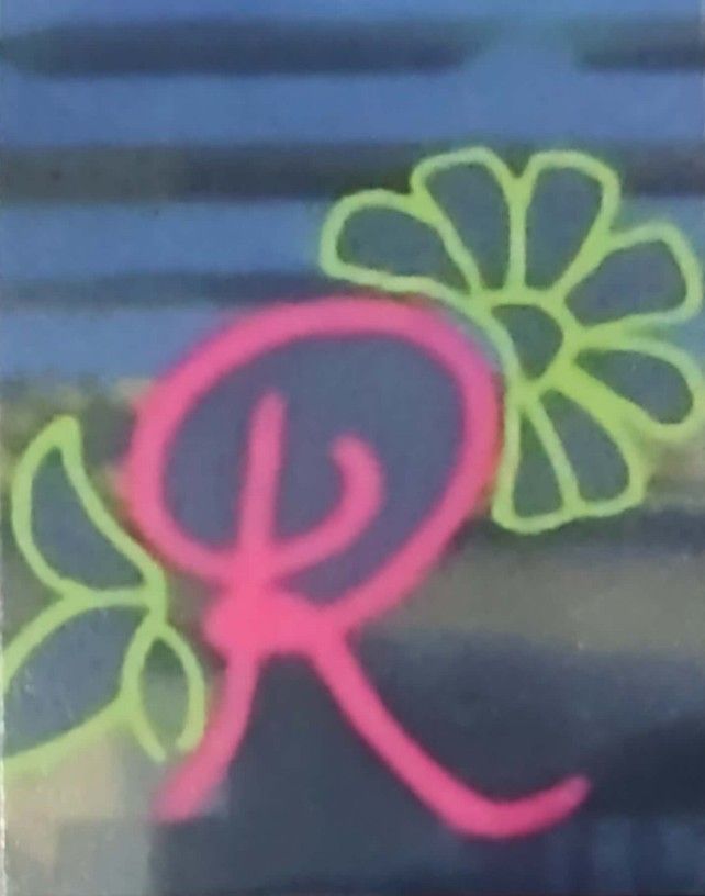 Letra "R" rosa con contornos de flores verdes.