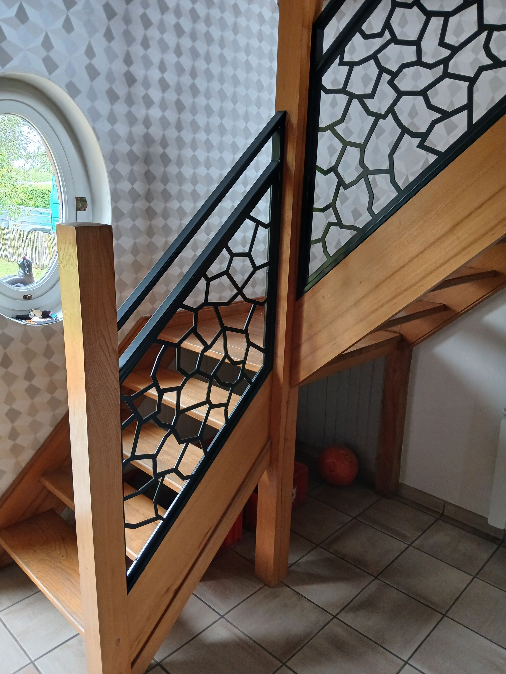 Escalier en bois avec rampe géométrique en métal noir.