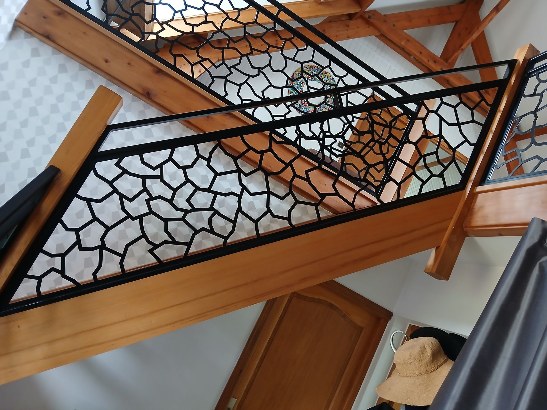 Escalier en bois avec rampe décorative noire, vu de face.