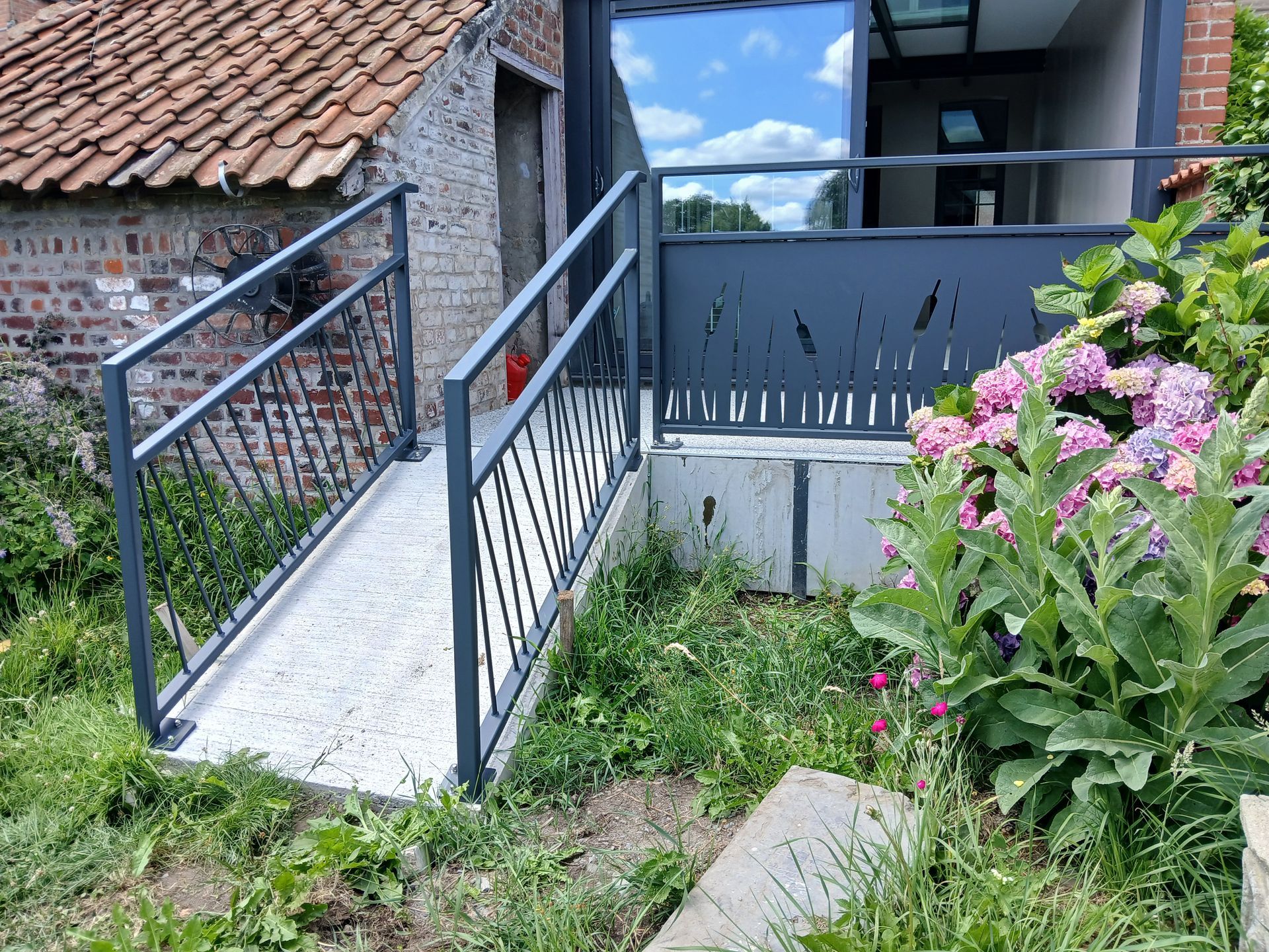 Rampe avec garde-corps métalliques menant à un bâtiment moderne.