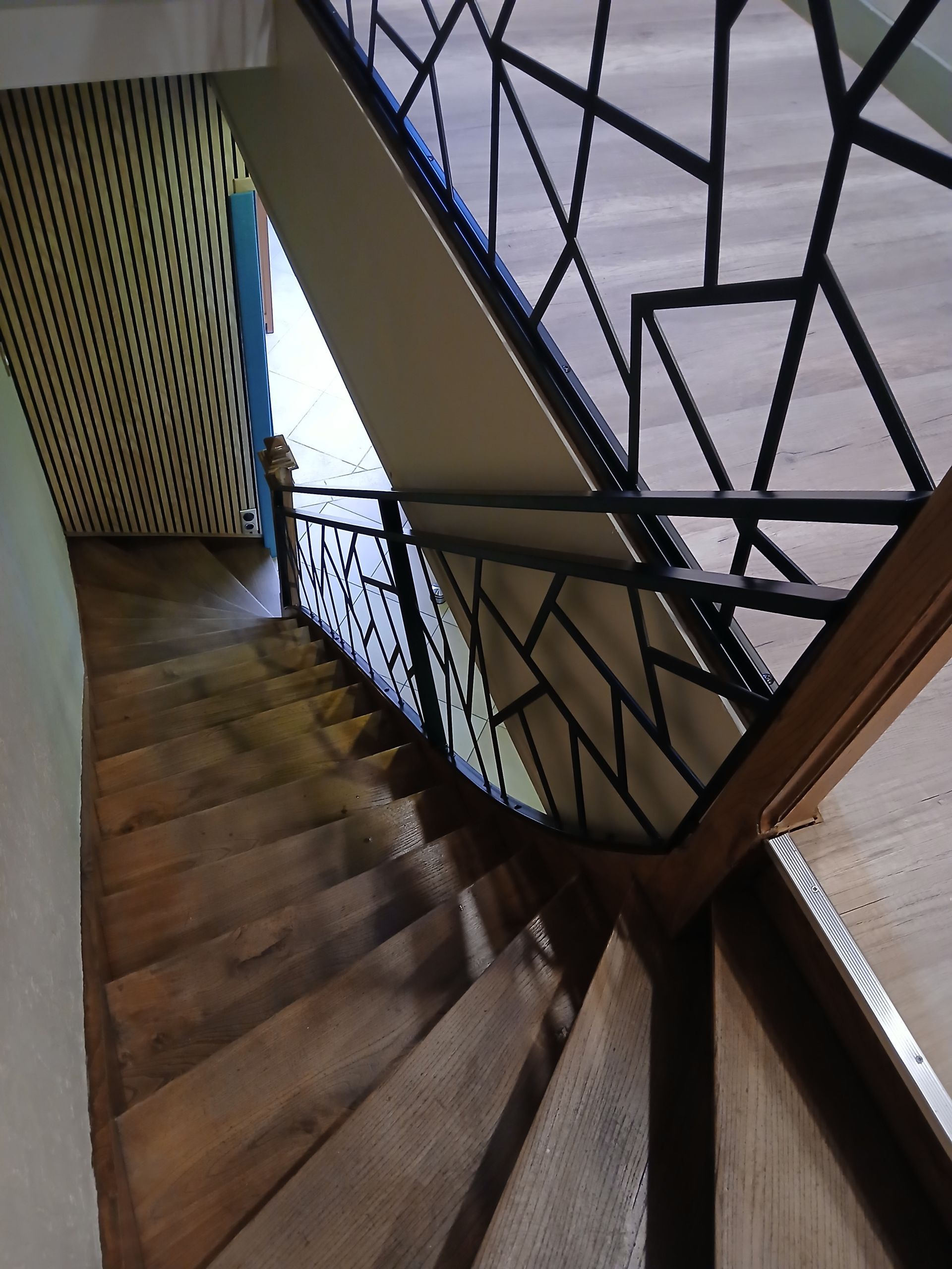 Escalier en bois avec rampe géométrique noire, vu de dessus.