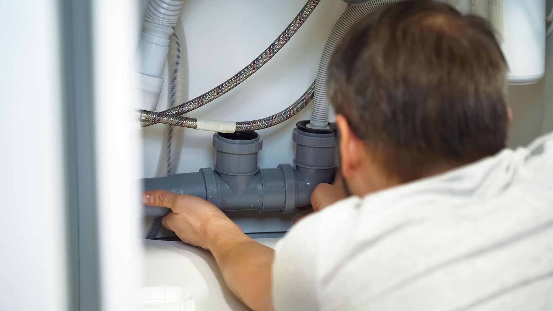 Un technicien inspecte les canalisations à l'intérieur d'une ouverture murale.