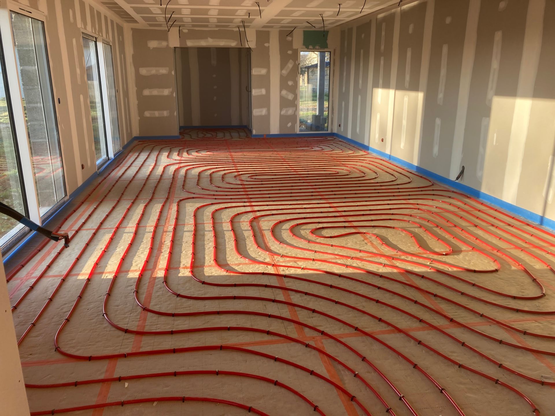 Des tubes de chauffage au sol sont installés dans une pièce en construction