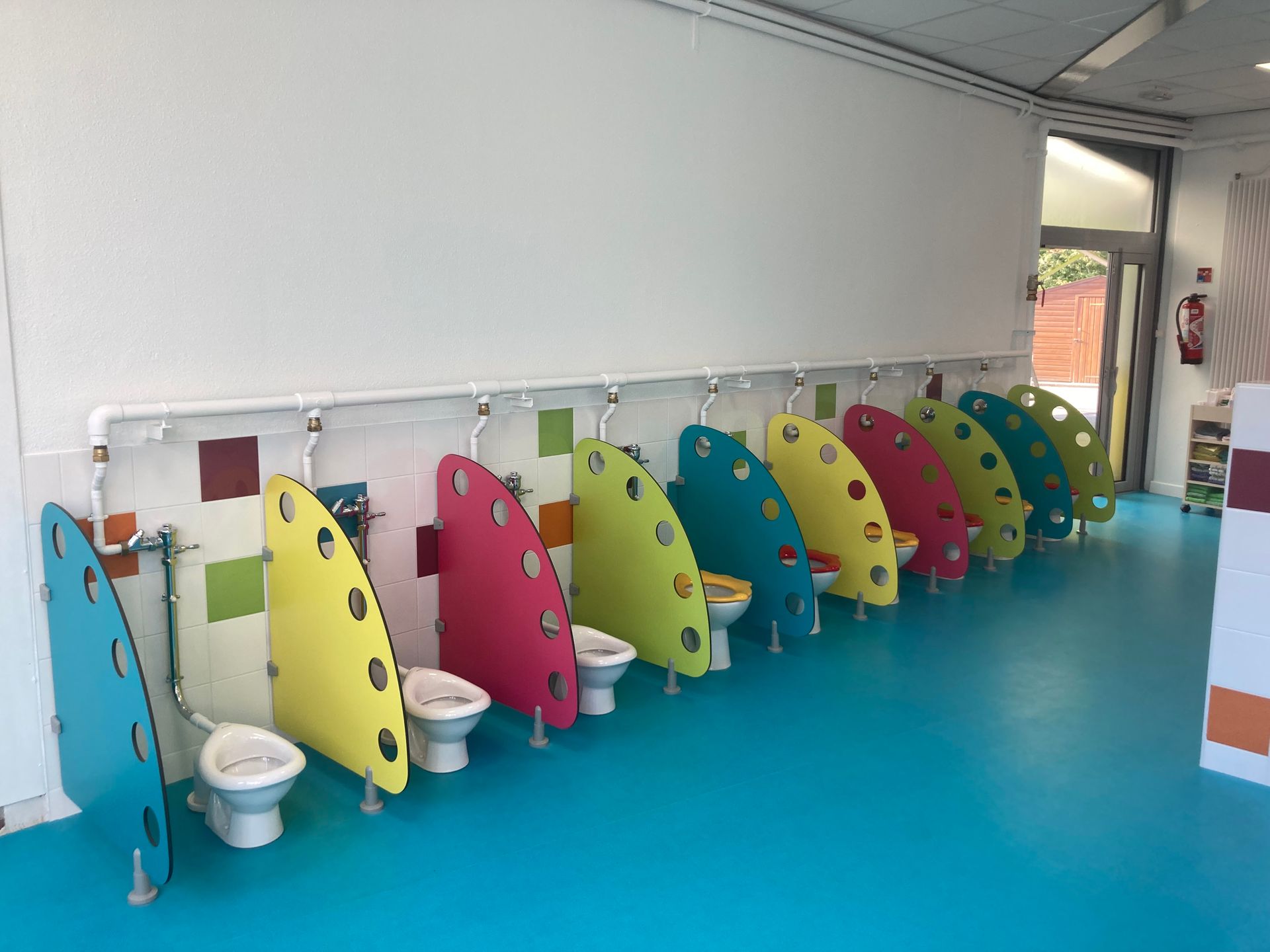 Rangée colorée d'urinoirs avec des séparateurs dans des toilettes lumineuses