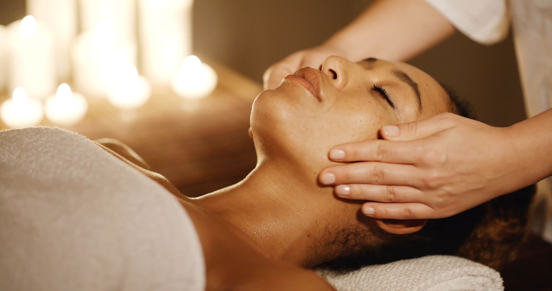 Une personne recevant un massage du visage dans un spa à l'éclairage tamisé.