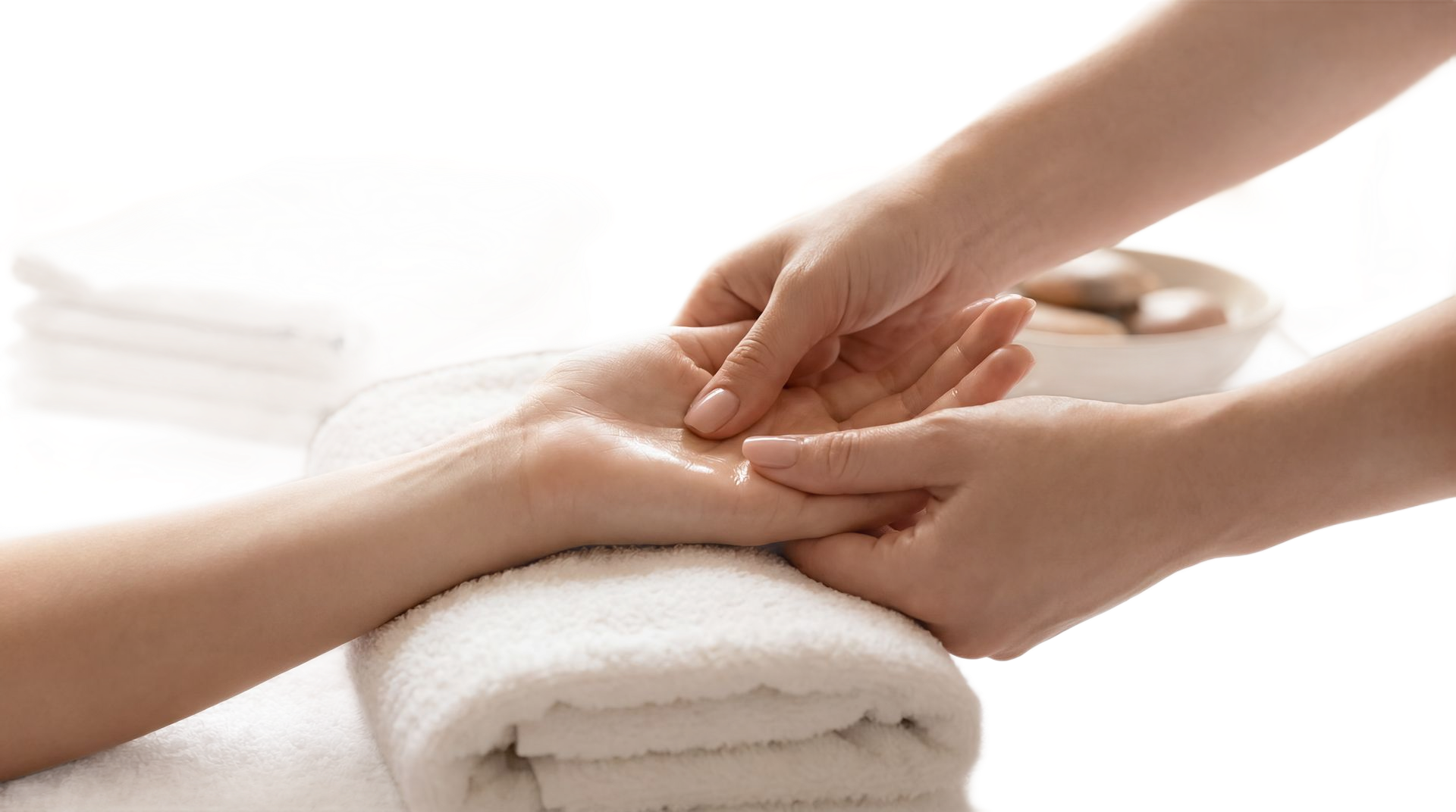 Des mains effectuent un massage sur une serviette blanche roulée dans un cadre de spa.