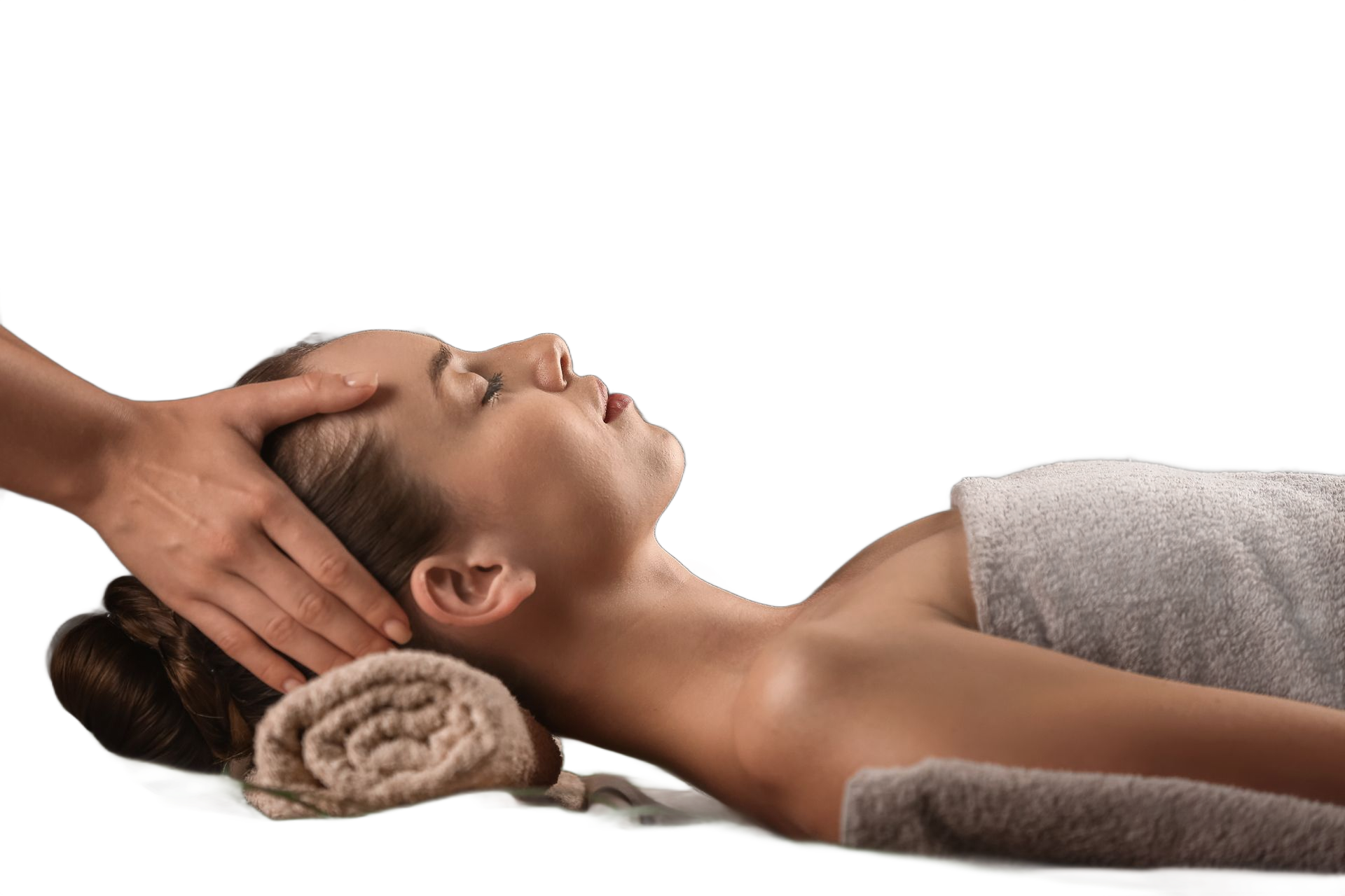 Une esthéticienne prodigue un massage de la tête à une femme allongée sur une serviette blanche, une serviette roulée sous sa nuque.