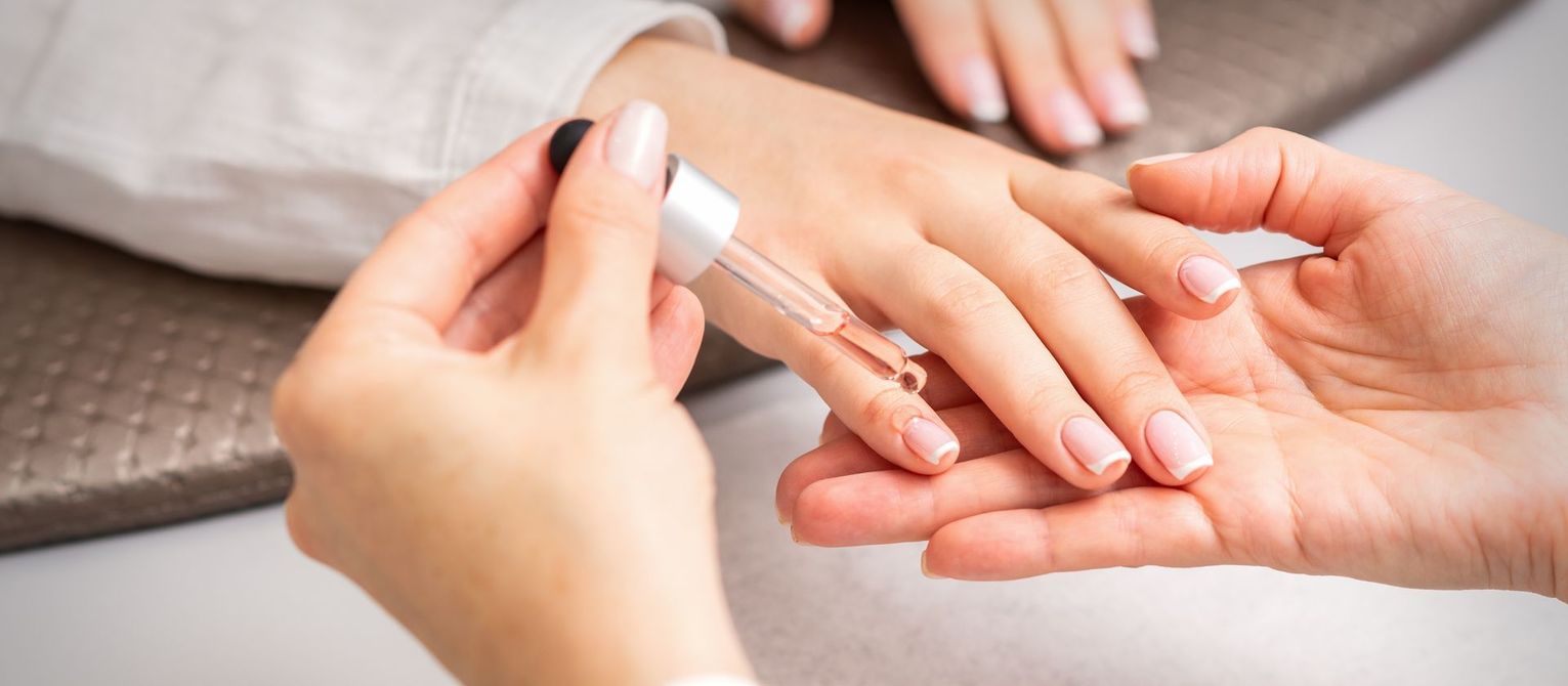 Des mains soignées reçoivent une manucure avec un vernis à ongles rose clair.