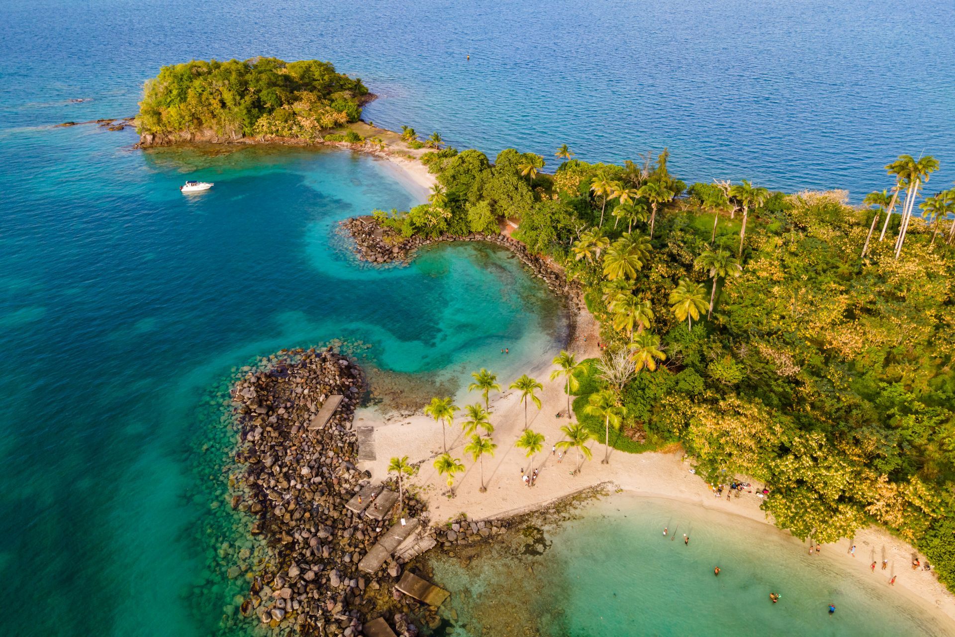 Vue aérienne d'une île tropicale aux eaux turquoise, aux plages de sable fin et aux palmiers luxuriants.