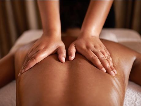 Des mains massent le dos d'une personne allongée sur le ventre sur une table de spa.