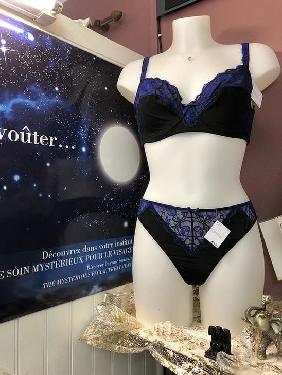 Ensemble de lingerie noire et bleue sur un mannequin à côté d'un présentoir d'affiches étoilées.