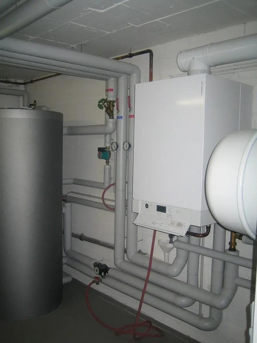 Heizungsanlage im Keller mit Boiler, Wassertank und Rohren.