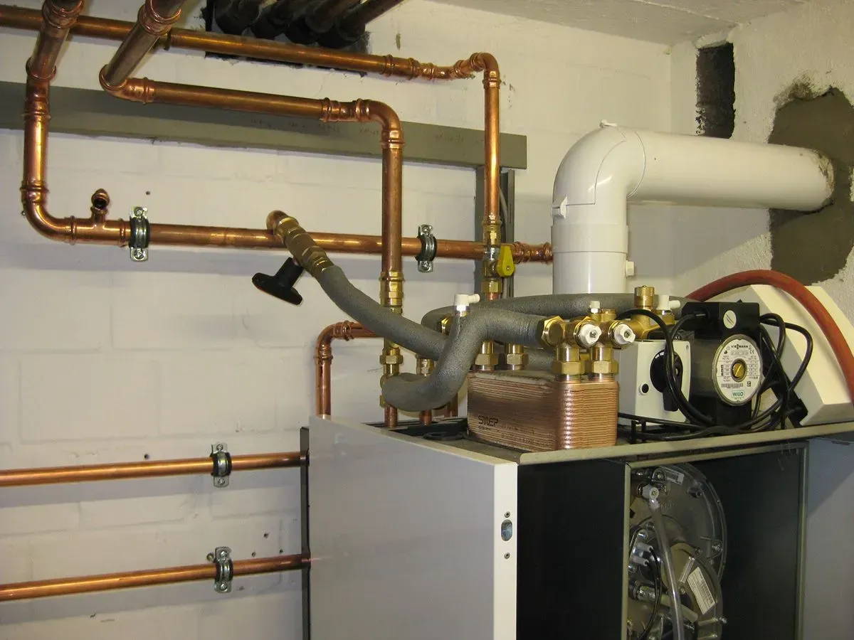 Kupferrohre und ein weißer Ofen in einem Keller.