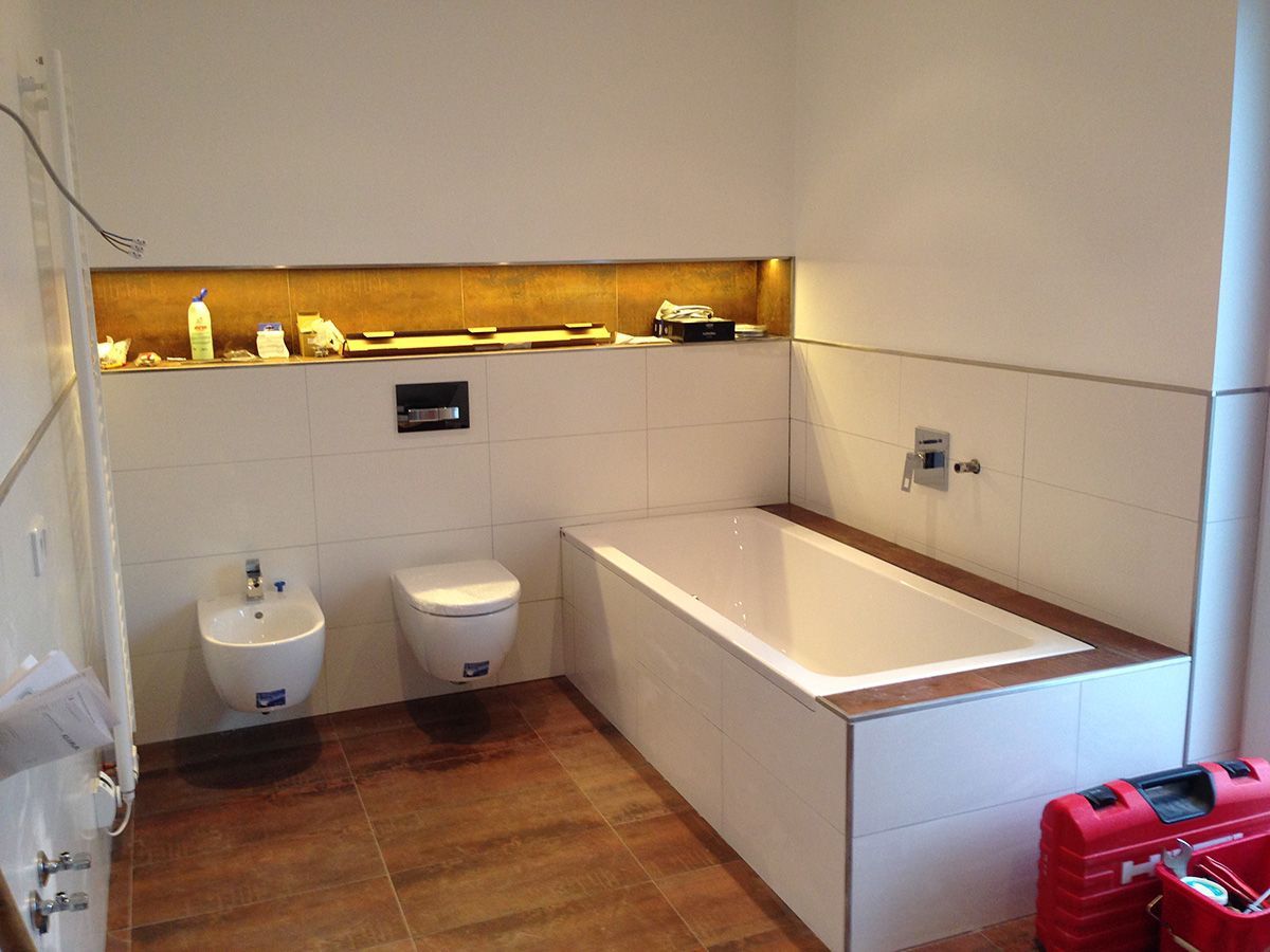 Badezimmer im Bau, mit Toilette, Bidet, Badewanne und eingebautem Regal; brauner Boden, weiße Wände.