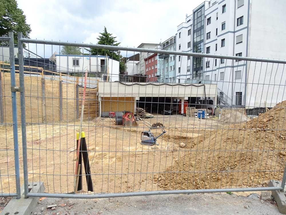 Eine Baustelle hinter einem Zaun mit einem Gebäude im Hintergrund