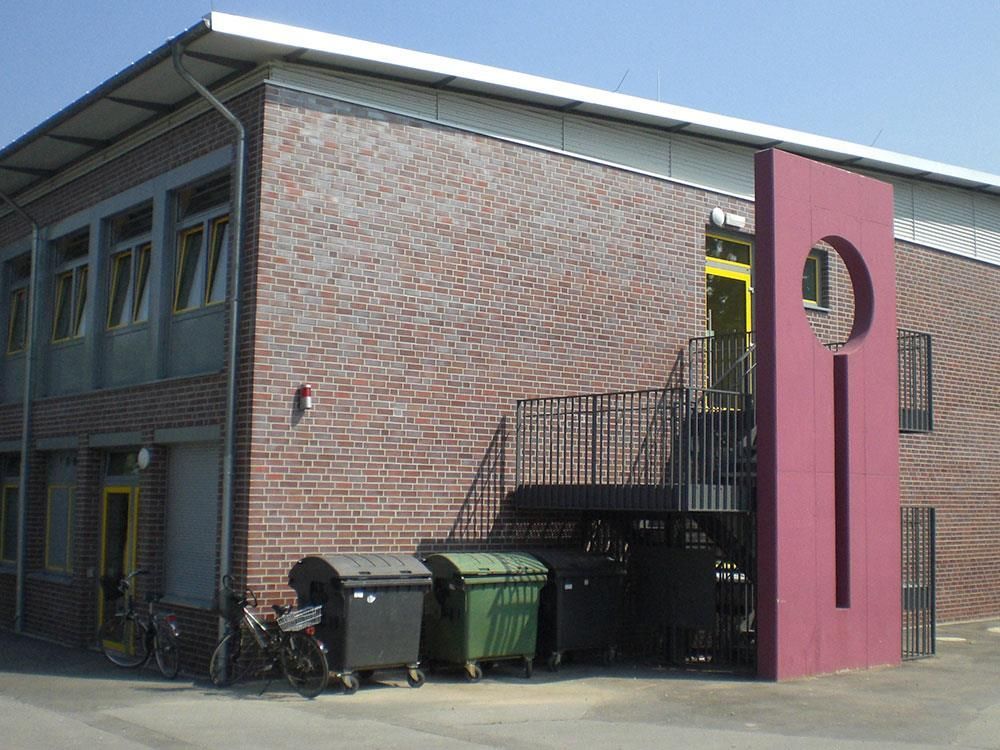 Ein Backsteingebäude mit einer rosa Säule und Treppe