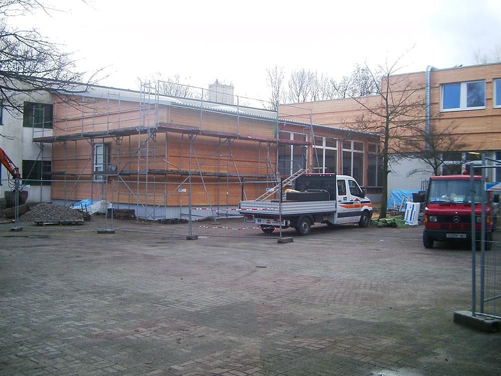 Ein roter LKW steht vor einem im Bau befindlichen Gebäude