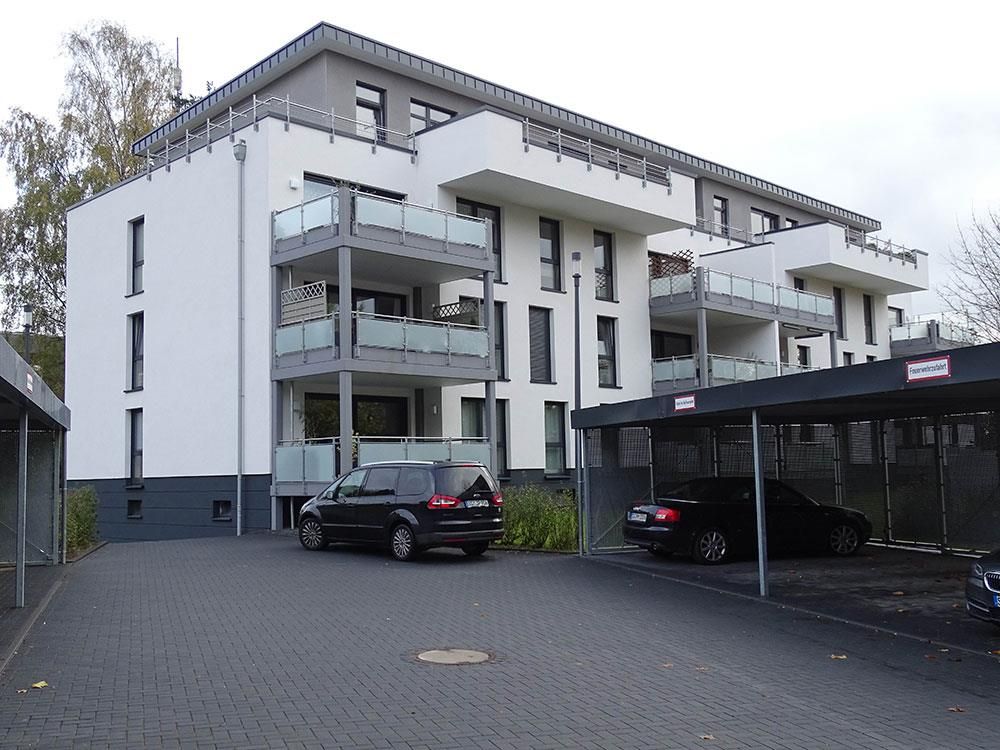 Ein schwarzes Auto steht vor einem weißen Gebäude