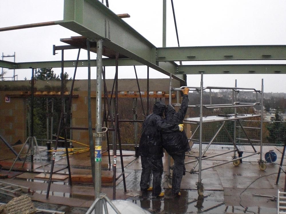 Zwei Bauarbeiter stehen im Regen auf einem Dach