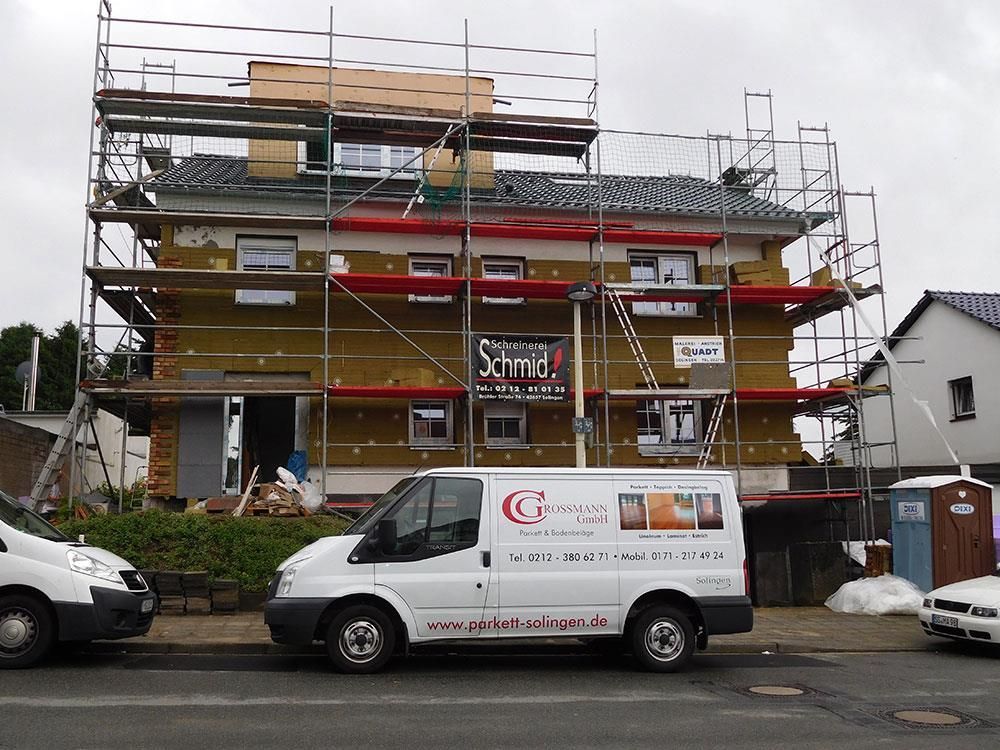 Ein weißer Lieferwagen steht vor einem im Bau befindlichen Gebäude