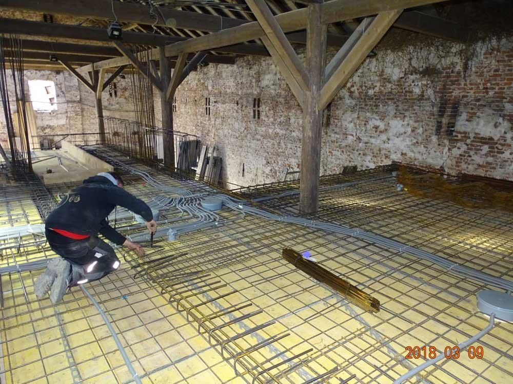 Ein Mann arbeitet auf einem Betonboden mit einer Ziegelwand im Hintergrund