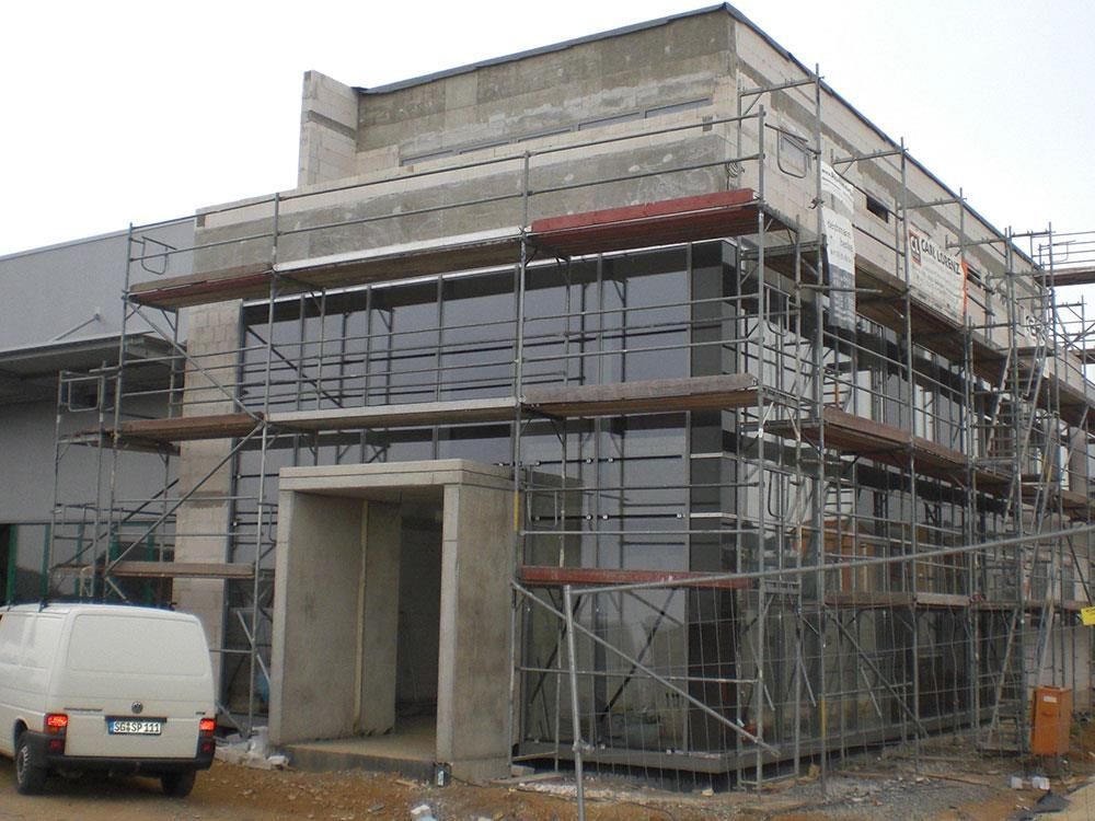 Ein weißer Lieferwagen steht vor einem im Bau befindlichen Gebäude