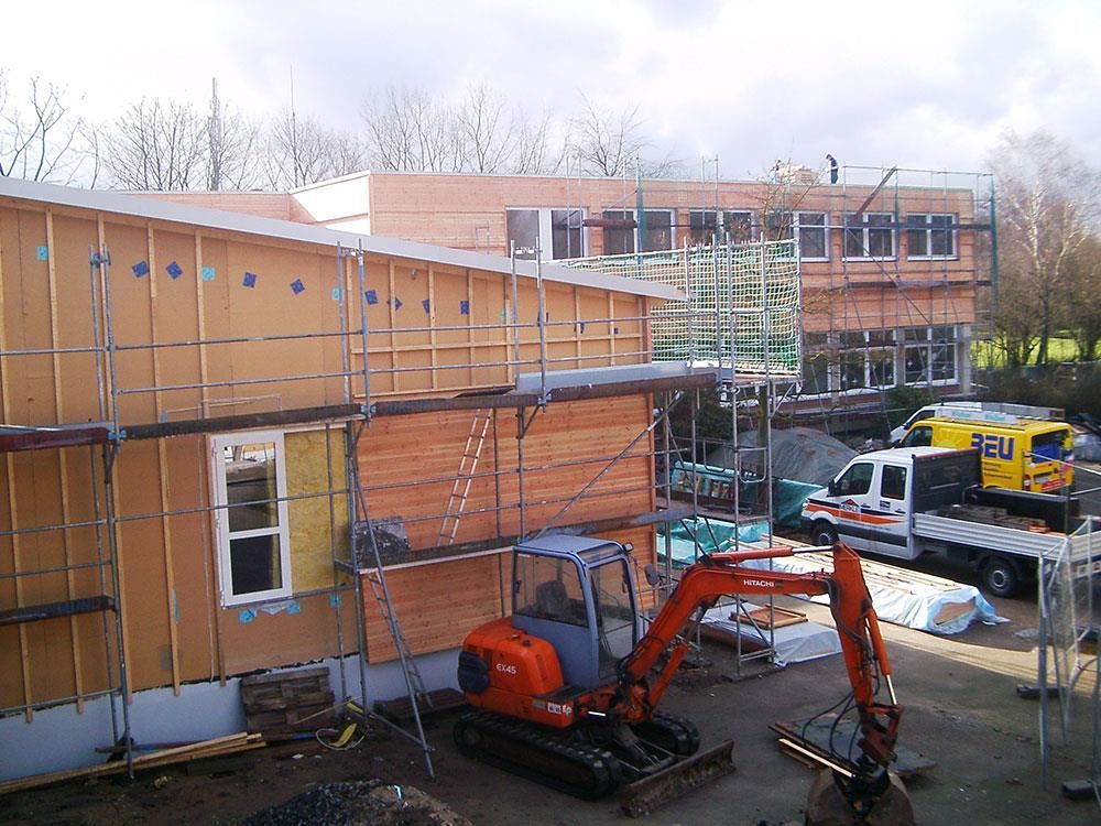 Ein orangefarbener Bagger steht vor einem im Bau befindlichen Gebäude