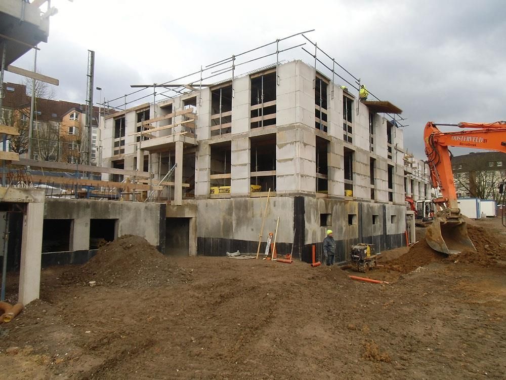 Eine Baustelle mit einem großen orangefarbenen Bagger im Vordergrund