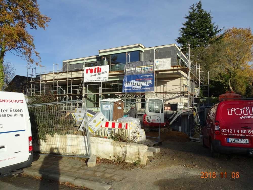 Ein im Bau befindliches Gebäude mit Gerüsten und einem roten Lieferwagen mit der Aufschrift „TCG“ darauf