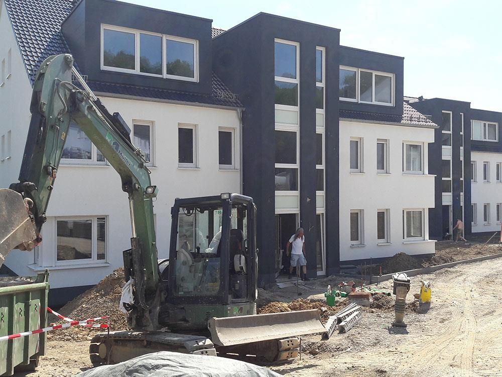 Ein grüner Bagger steht vor einem im Bau befindlichen Gebäude
