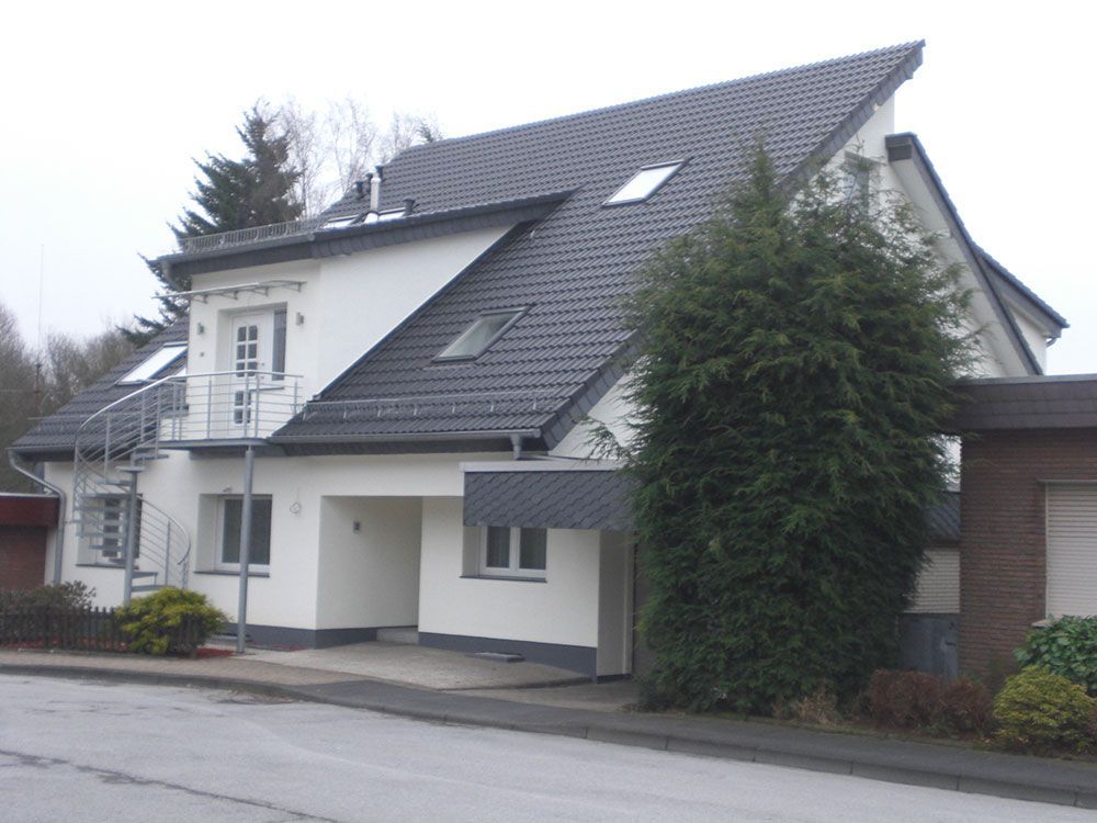 Ein weißes Haus mit schwarzem Dach und Treppen