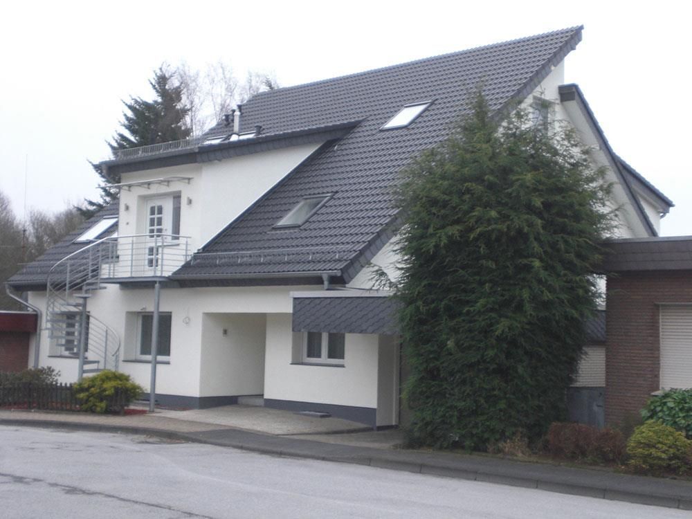 Ein weißes Haus mit schwarzem Dach und Treppen